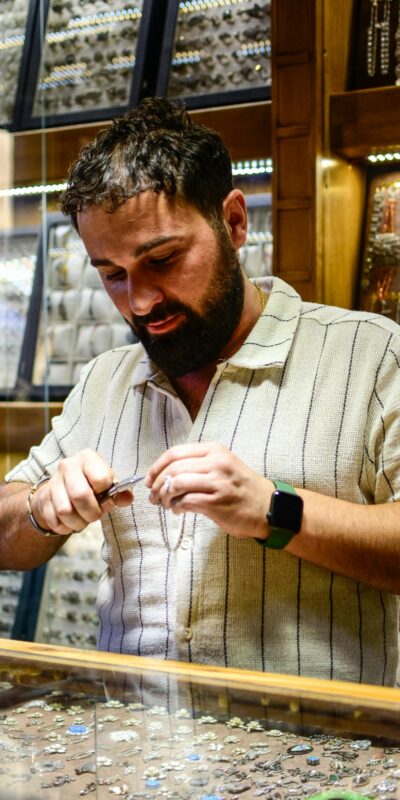 A bearded jeweller inspects jewelry in a shop, showcasing his craft and expertise.