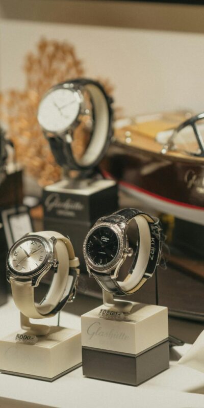 A collection of luxury watches elegantly displayed beside a model boat in a retail environment.
