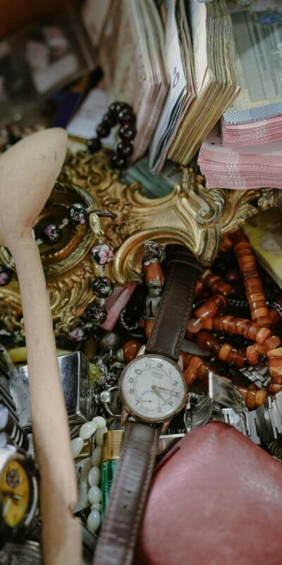 Close-up of assorted vintage watches, jewelry, and currency at a flea market.