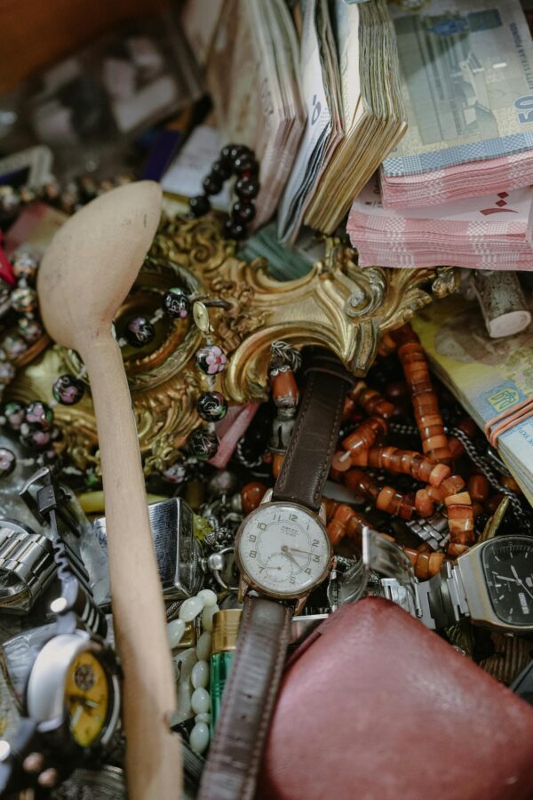 Close-up of assorted vintage watches, jewelry, and currency at a flea market.