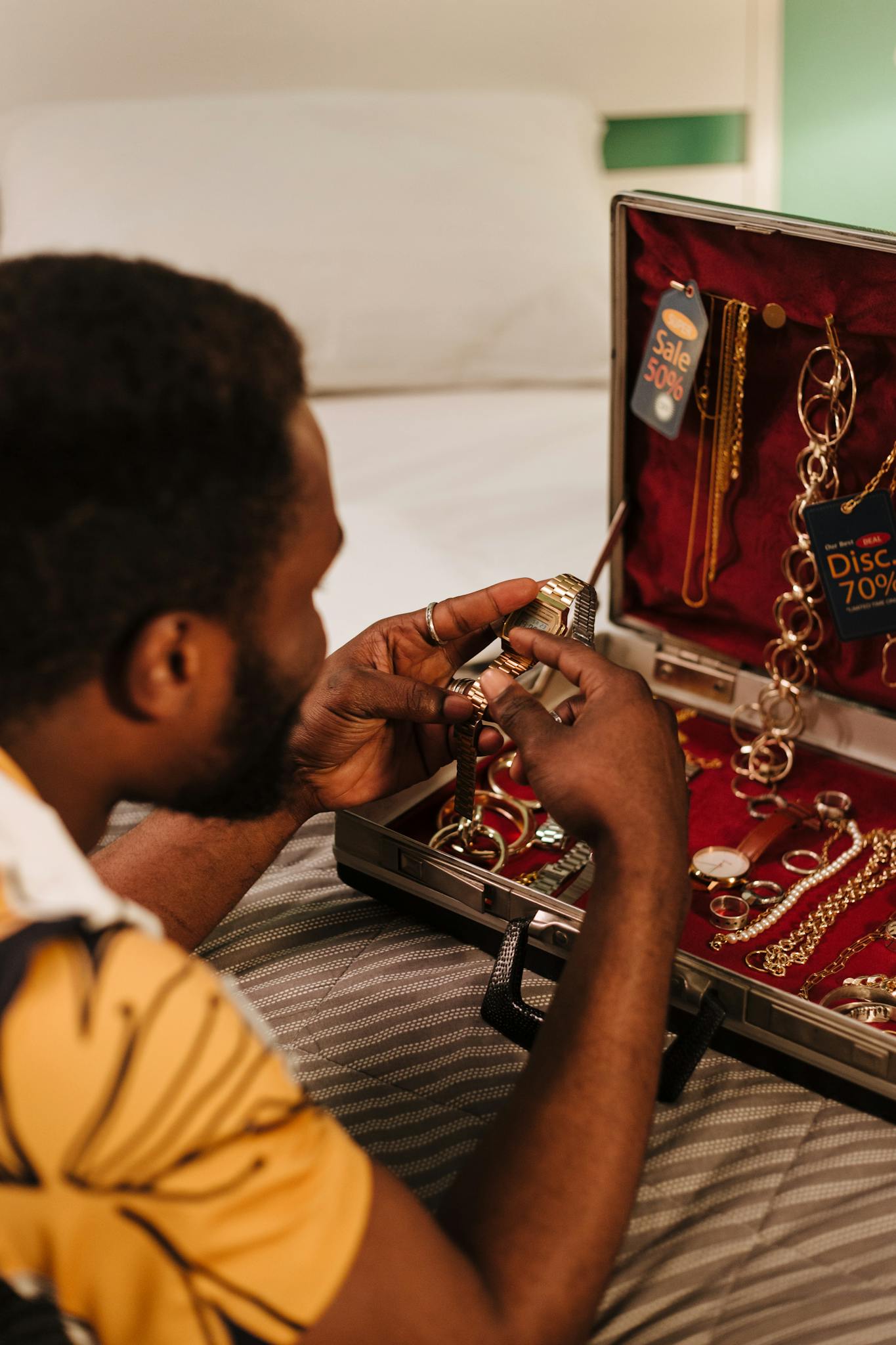 Man inspecting jewelry in suitcase with sale tags, indoors.